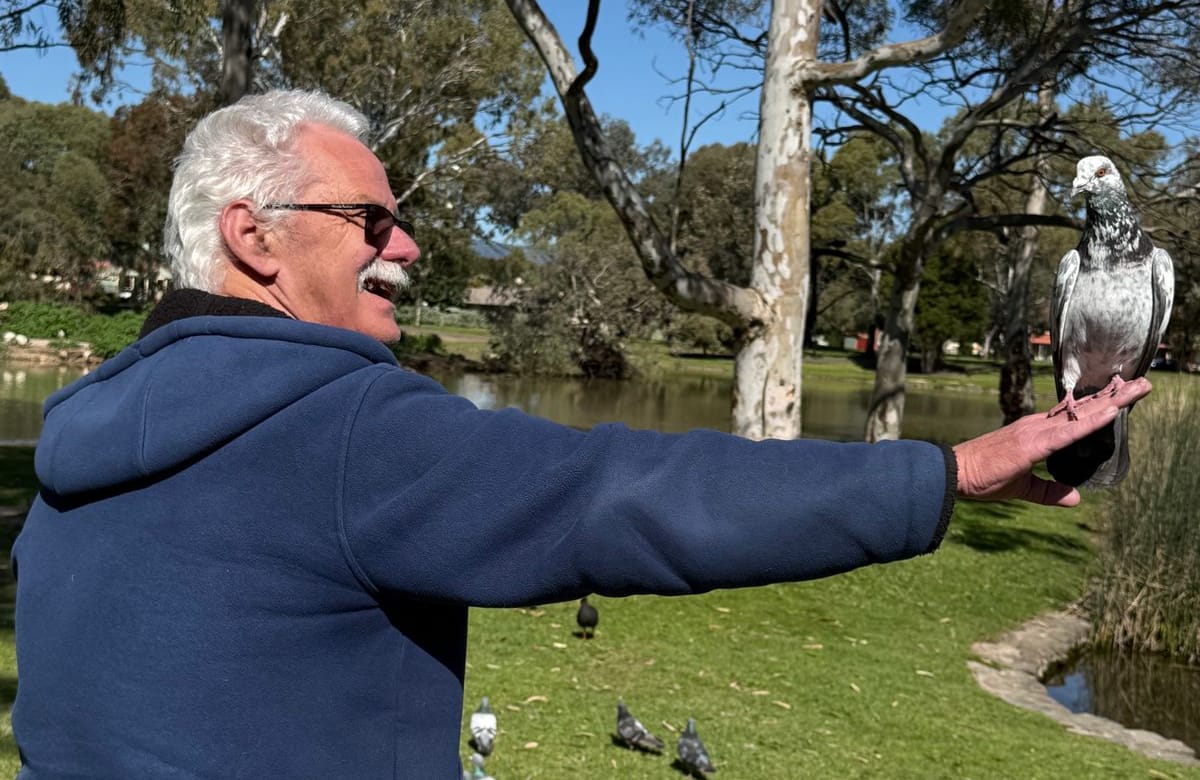 A participant smiling as a pigeon lands on his outstretched hand at a local park