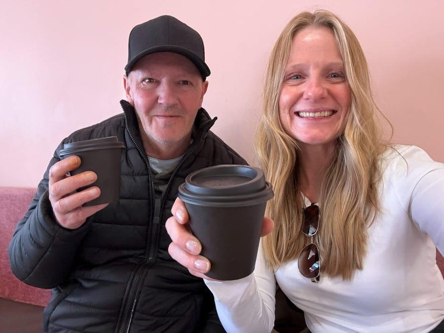 A participant and support worker sharing a takeaway coffee together