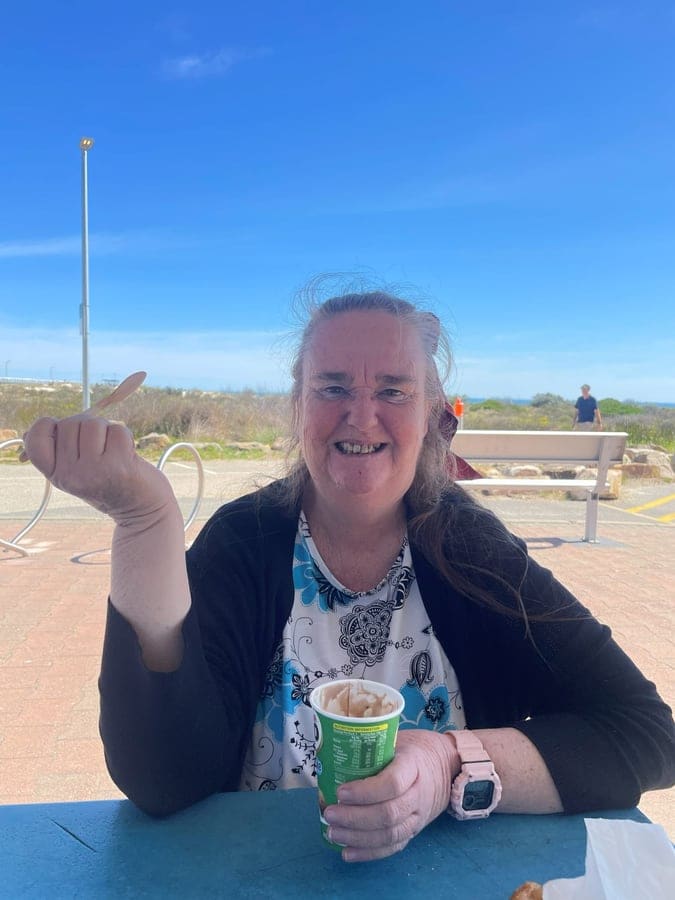 A participant enjoying an ice cream by the beach on a sunny outing