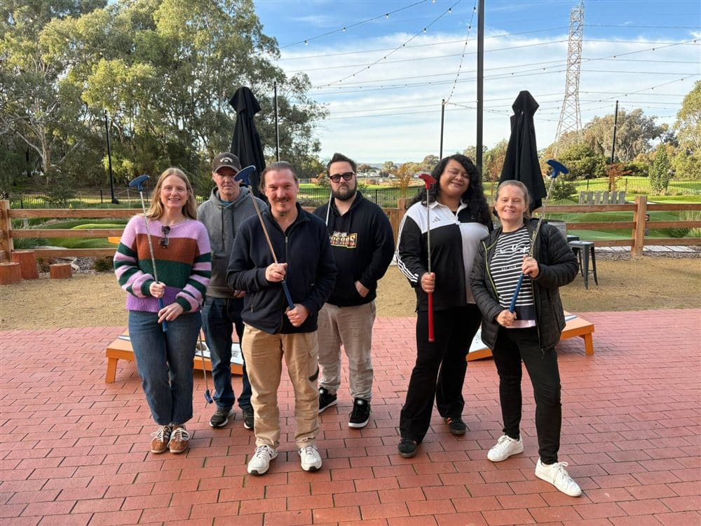A group of participants and support workers together at a mini golf outing