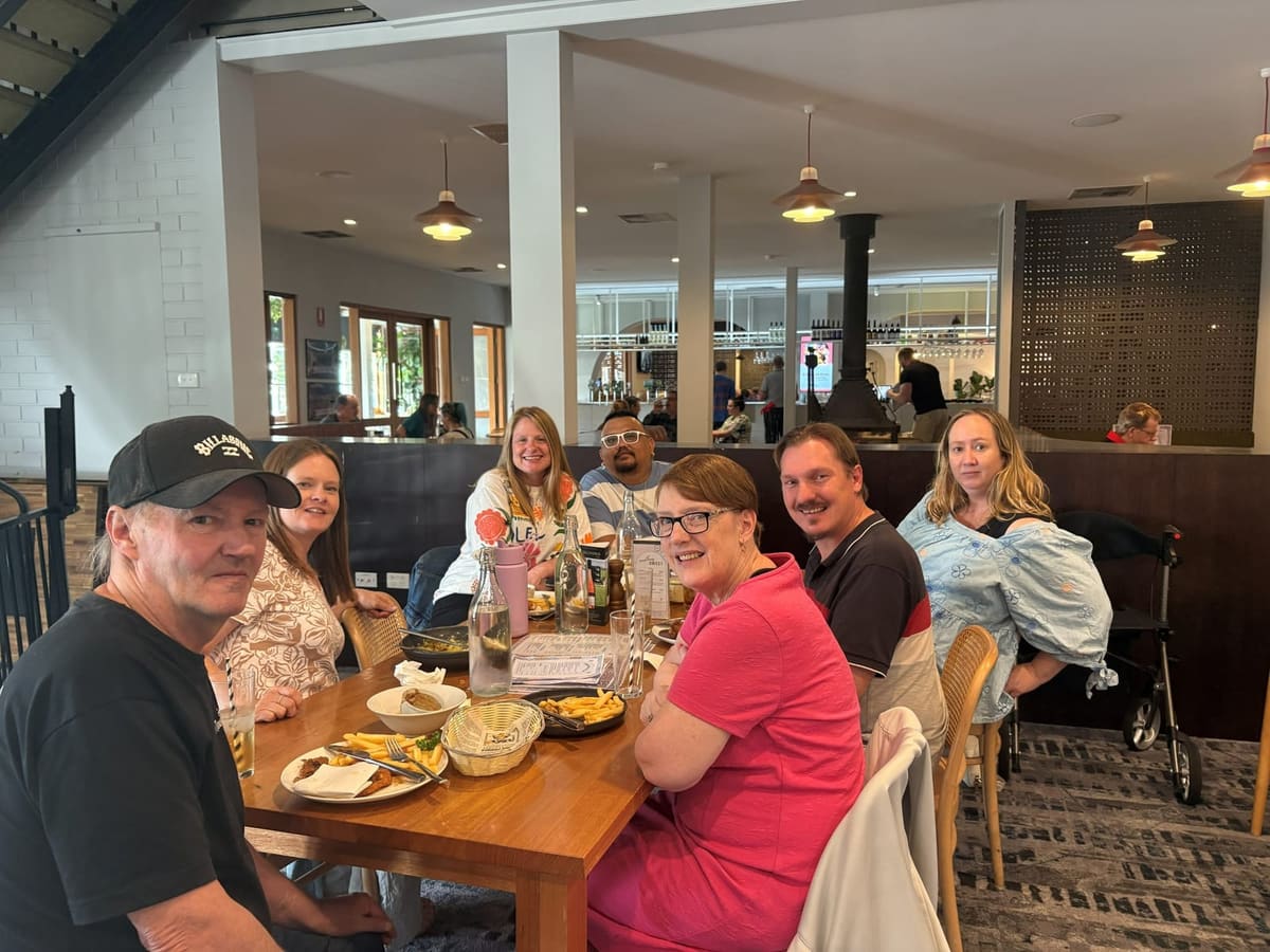 A group of participants and support workers sharing a meal together at a cafe